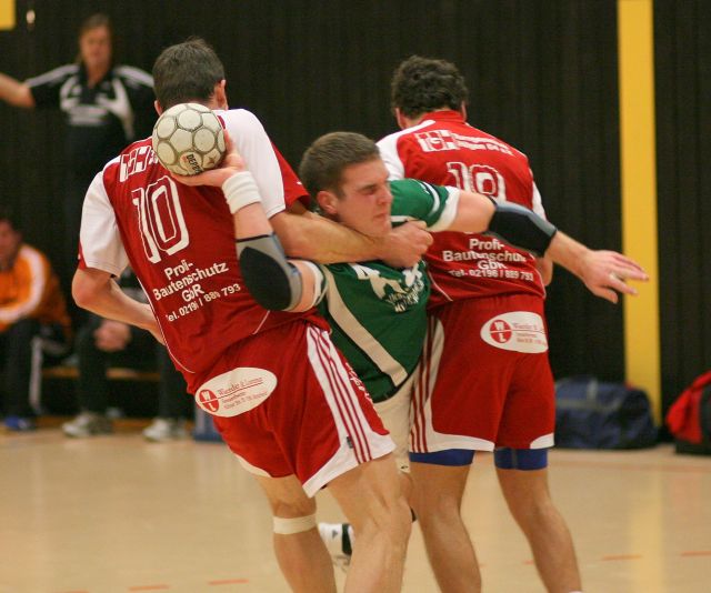 Ein Handballer versucht sich gegen zwei Gegenspieler durchzusetzen